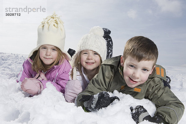 Deutschland  Bayern  München  Kinder (4-5) (8-9) im Schnee liegend  Portrait