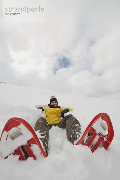 Italien  Südtirol  Junge Frau mit im Schnee liegenden Schneeschuhen