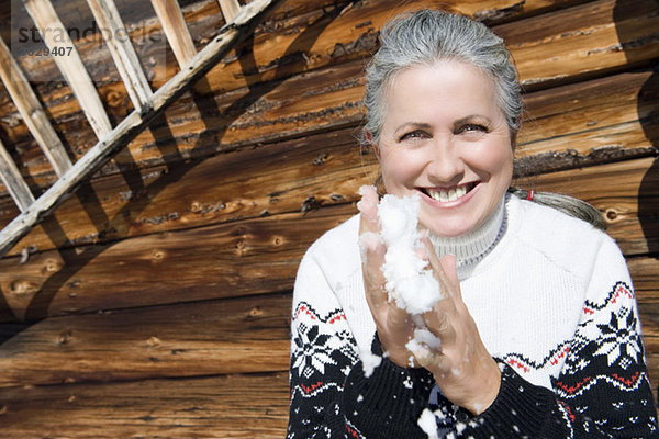 Italien  Südtirol  Seiseralm  Seniorin mit Schnee in den Händen  lächelnd  Portrait