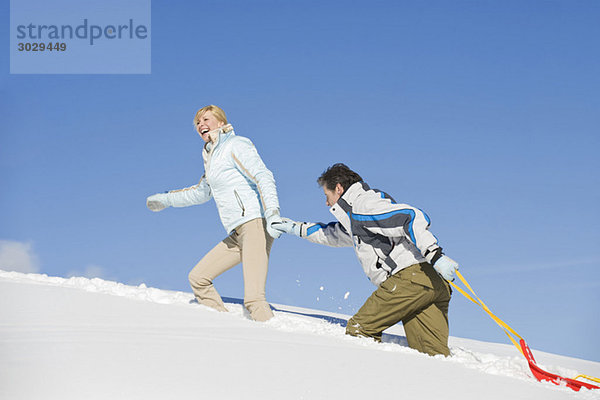Italien  Südtirol  Seiseralm  Paar Wandern im Schnee  Schlittenziehen
