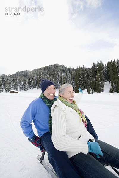Italien  Südtirol  Seiseralm  Seniorenpaar Rodeln  Lachen  Portrait