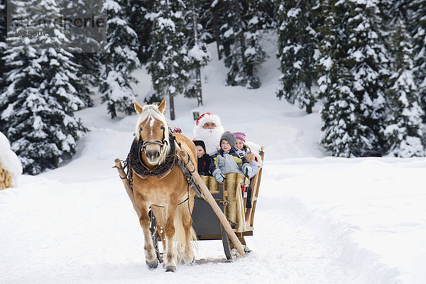 Italien  Südtirol  Seiseralm  Weihnachtsmann und Kinder beim Schlittenfahren