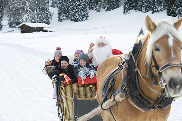 Italien  Südtirol  Seiseralm  Weihnachtsmann und Kinder sitzen im Schlitten