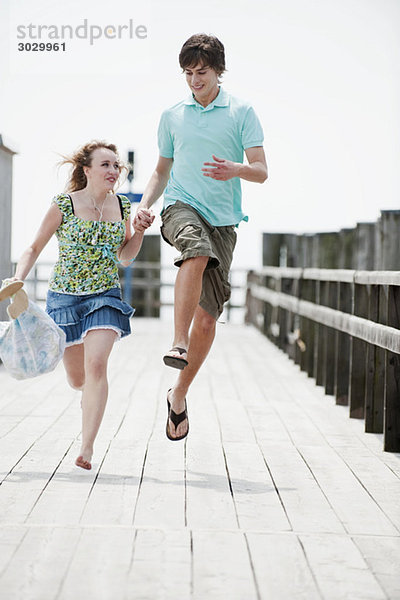 Germany  Bavaria  Ammersee  Young couple running on pier