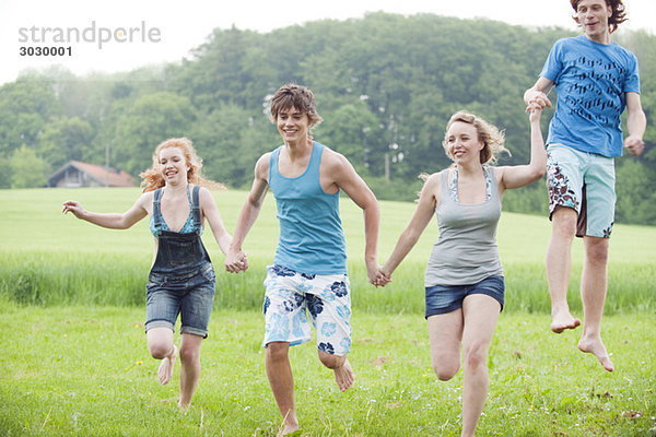 Germany  Bavaria  Young people running across meadow