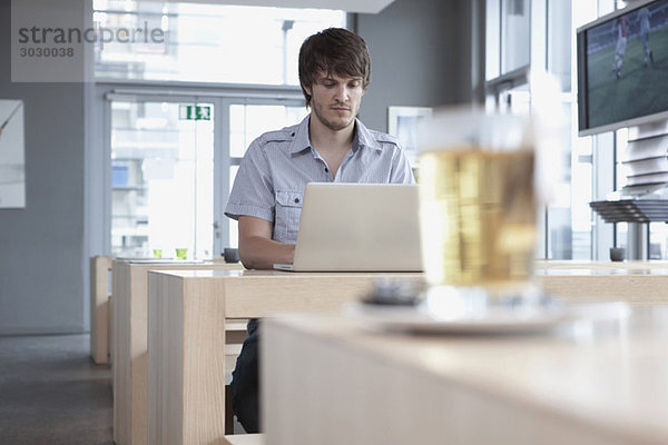 Junger Mann im Cafe mit Laptop