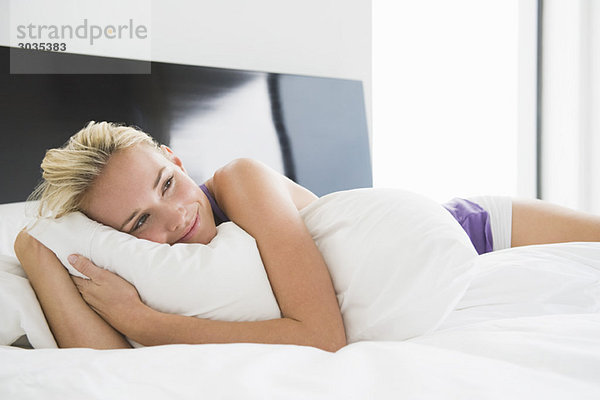 Frau umarmt ein Kissen auf dem Bett