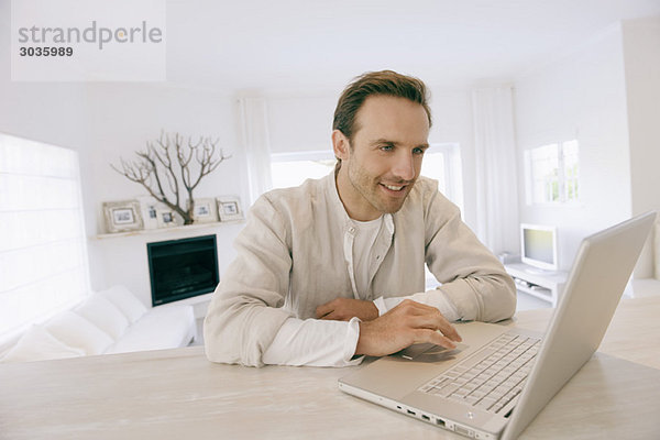 Mann arbeitet an einem Laptop und lächelt