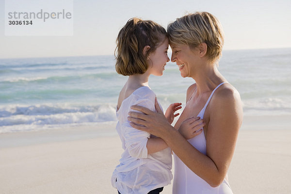 Frau mit ihrer Tochter beim Nasenreiben am Strand