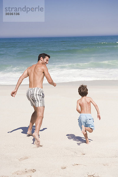 Mann  der mit seinem Sohn am Strand läuft