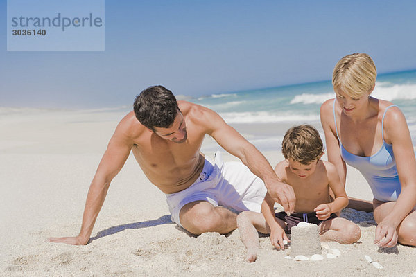 Familie beim Bau einer Sandburg am Strand
