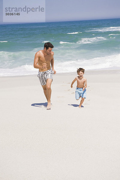 Mann  der mit seinem Sohn am Strand läuft