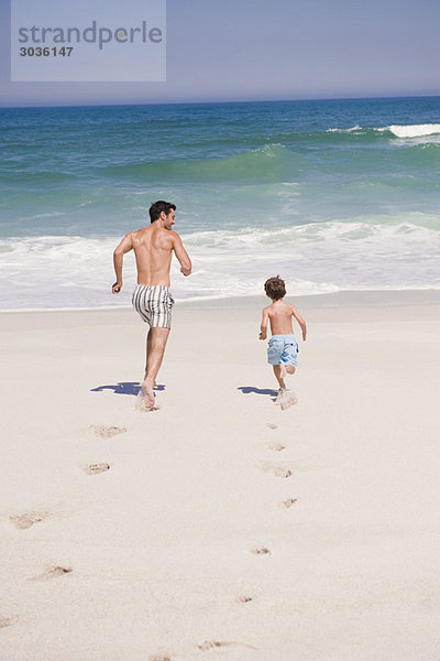 Mann  der mit seinem Sohn am Strand läuft