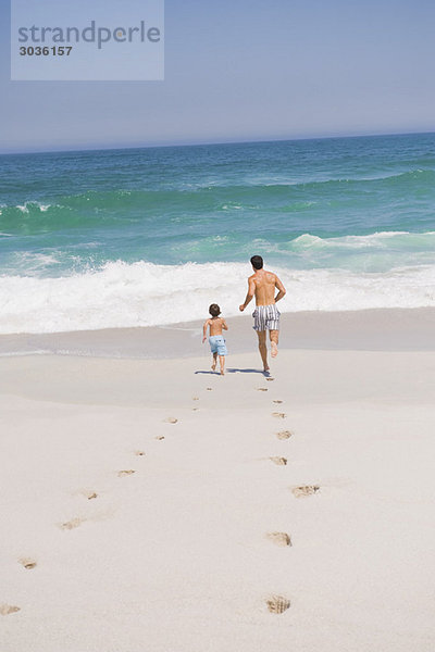 Mann  der mit seinem Sohn am Strand läuft