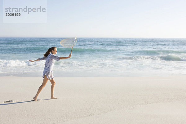 Frau mit Fischernetz am Strand