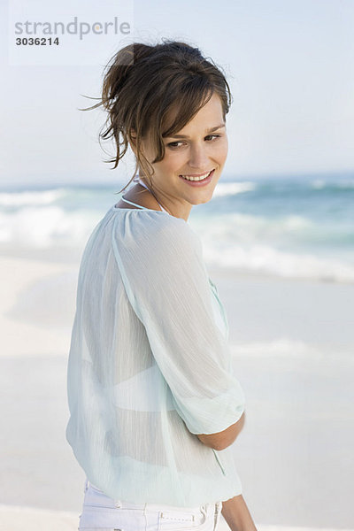 Frau am Strand stehend und lächelnd