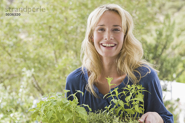 Frau trägt Pflanzen und lächelt