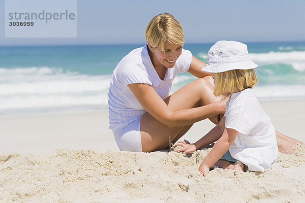 Frau sitzend mit ihrer Tochter am Strand