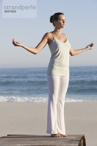 Frau praktiziert Yoga auf einer Strandpromenade