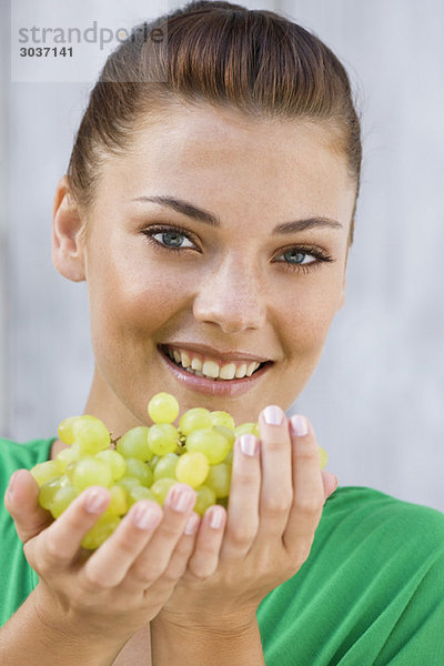 Frau hält Weintrauben und lächelt