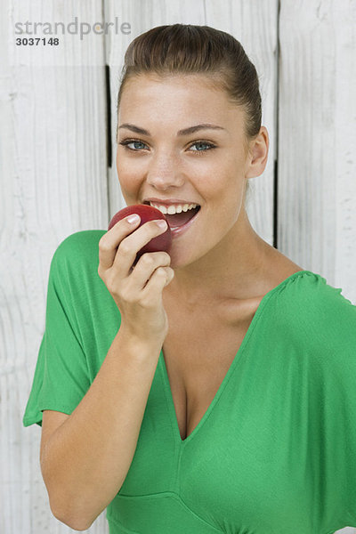 Frau isst einen Apfel und lächelt