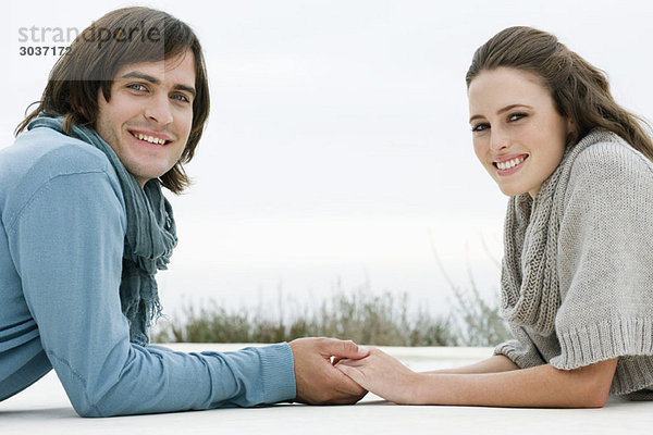 Ein Paar hält sich an den Händen und lächelt.