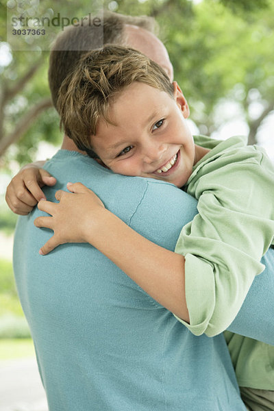Junge umarmt seinen Vater und lächelt