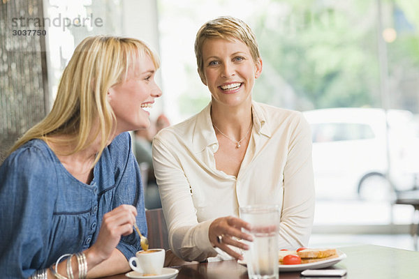 Zwei Frauen  die in einem Restaurant sitzen und lächeln.