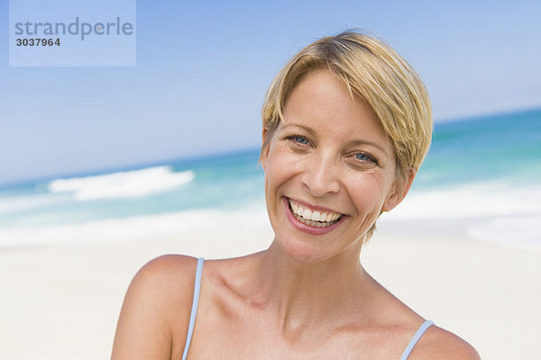 Porträt einer am Strand lächelnden Frau