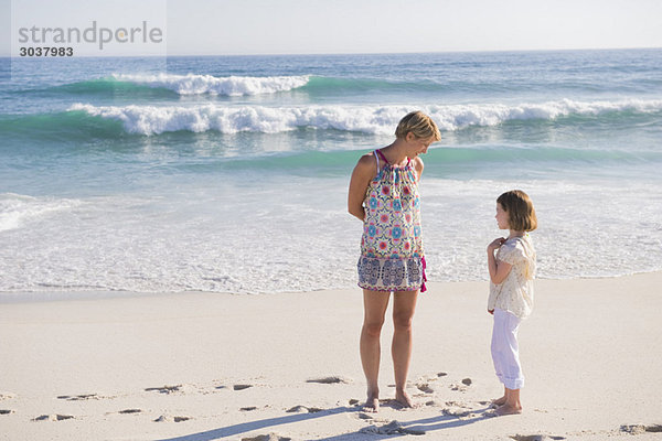 Frau am Strand stehend mit ihrer Tochter