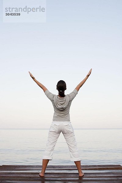 Junge Frau beim Yoga am Steg