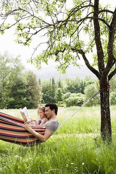 Vater und Tochter lesen in der Hängematte