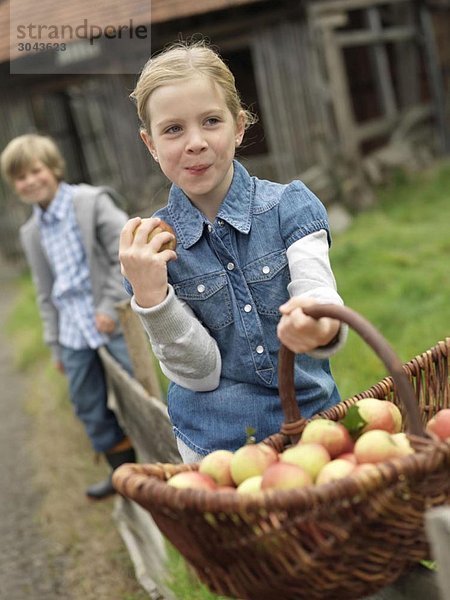 Mädchen mit Apfelkorb essen Äpfel