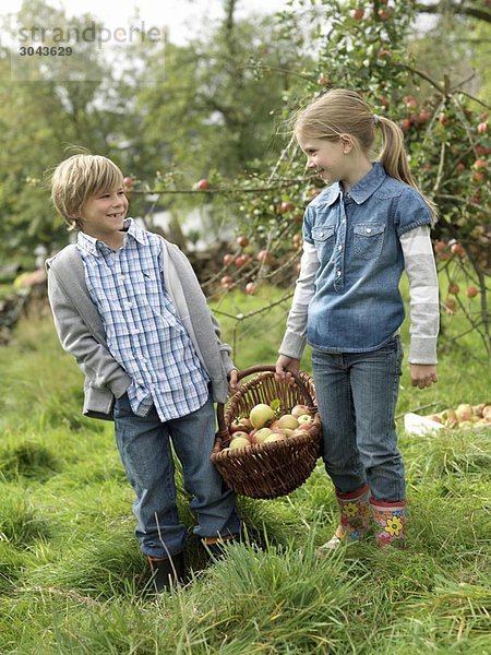 Mädchen und Junge mit Apfelkorb
