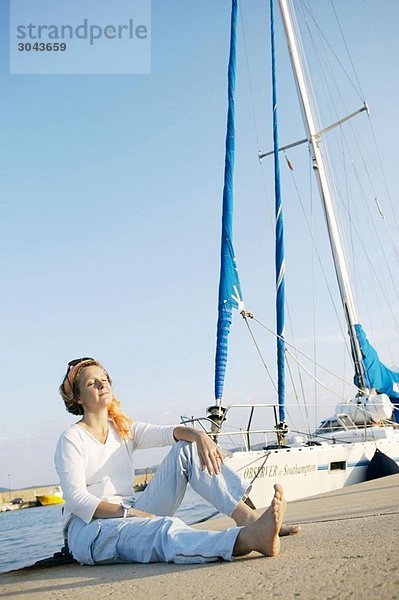 Frau entspannt am Hafen neben dem Boot