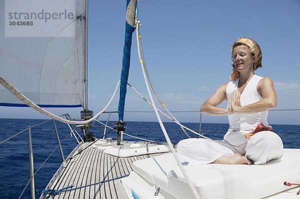Frau beim Yoga auf dem Segelboot
