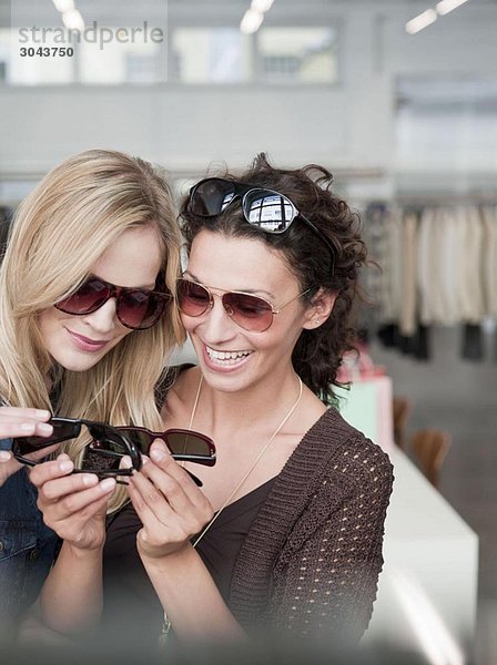 Frauen beim Einkaufen vergleichen Sonnenbrillen