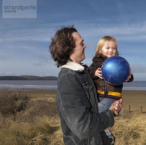 Vater und Sohn am Strand beim Ballspielen