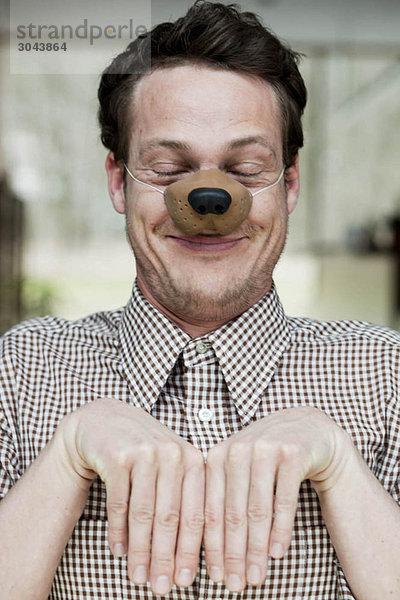 Mann mit Spielzeug Hundenase lächelnd