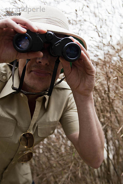 Mann im Dschungel-Outfit mit Fernglas