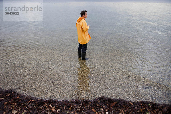 Mann im Regenmantel im Flachwasser