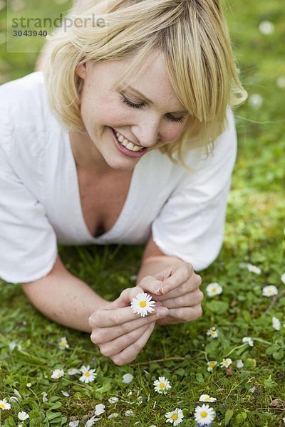 Frau im Garten liegend mit Blume