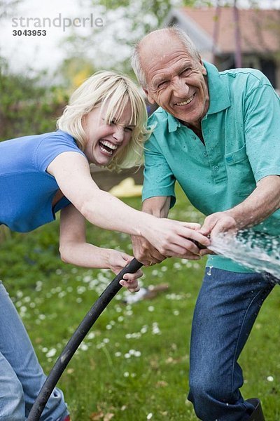 Frau und alter Mann spielen mit dem Schlauch