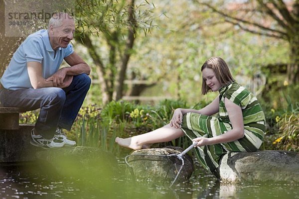 alter Mann und junges Mädchen am Teich