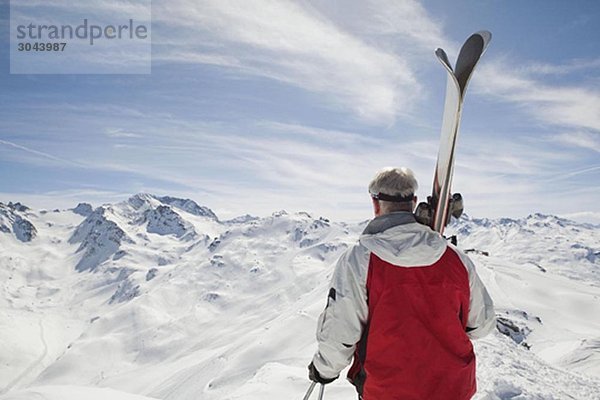 Rückansicht des reifen Mannes mit den Skiern