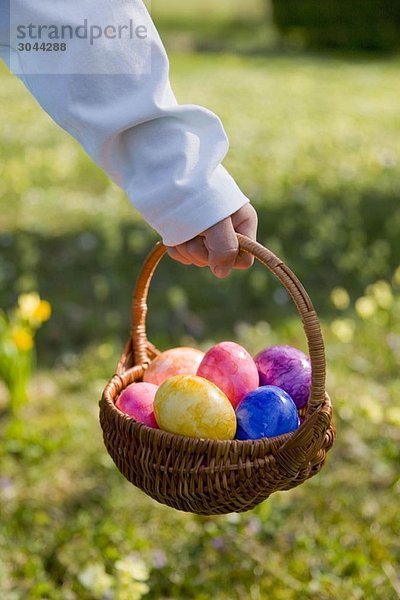 Junge hält Osterkorb  bemalte Eier