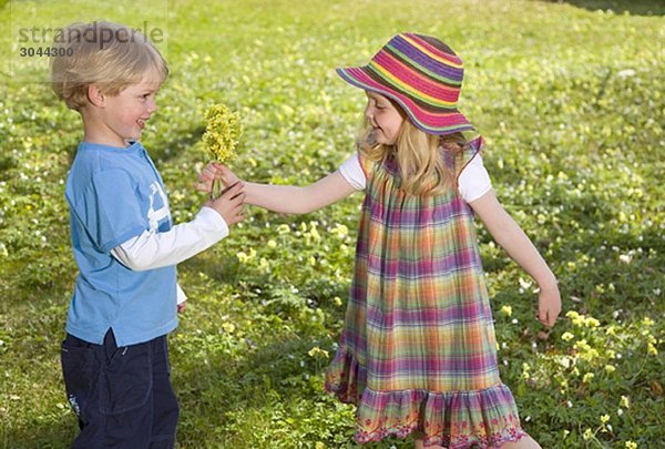 Mädchen schenkt Frühlingsblumenstrauß an Jungen