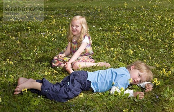 Mädchen und Junge im Gras liegend