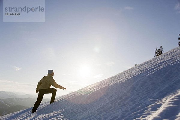 Mann klettert auf den verschneiten Berg