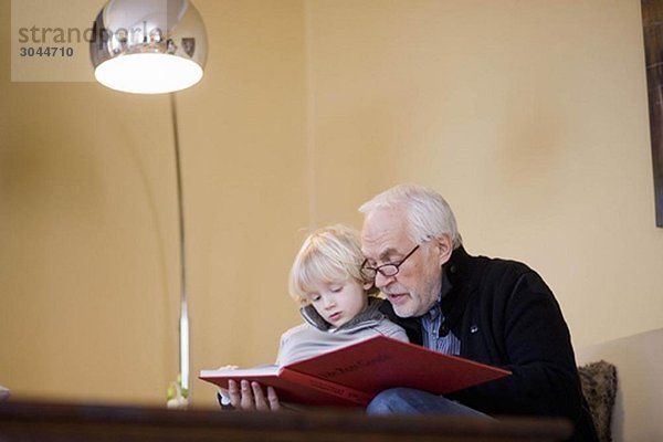 alter Mann  der dem kleinen Jungen das Buch vorliest.